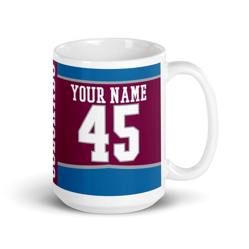 May include: White ceramic mug with a burgundy, gray, and blue design. The design features the text "YOUR NAME" and the number "45" in white.