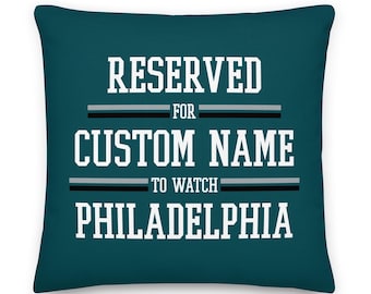May include: Teal blue throw pillow with white text that reads "RESERVED FOR CUSTOM NAME TO WATCH PHILADELPHIA".
