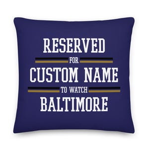 Pode incluir: Uma almofada azul marinho com texto branco que diz "RESERVED FOR CUSTOM NAME TO WATCH BALTIMORE". O texto é destacado em dourado.