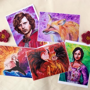 May include: Set of five watercolour art prints featuring a man with curly hair, a fox, a person with wings, a woman in a purple dress, and a woman in a black and white suit. The prints are on white cardstock and have a watercolour background.