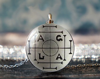 May include: A silver pendant necklace with a round, clear glass charm featuring a black and white design of a circle with four lines extending from the center, each line ending in a letter: H, A, G, L. The letters are arranged in a square pattern around the circle.