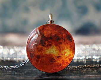 May include: A silver chain necklace with a round pendant featuring a detailed image of the planet Jupiter. The pendant has a glass-like finish and shows the planet's swirling red, orange, and yellow clouds.