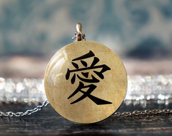 May include: A silver chain necklace with a round pendant featuring the Chinese character for "love" in black on a textured, cream-colored background.