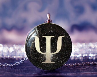 May include: A silver chain necklace with a round pendant featuring a black background with a white glitter finish and a white Greek letter psi symbol.