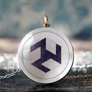 May include: A silver chain necklace with a round pendant featuring a white and purple geometric symbol on a white background.