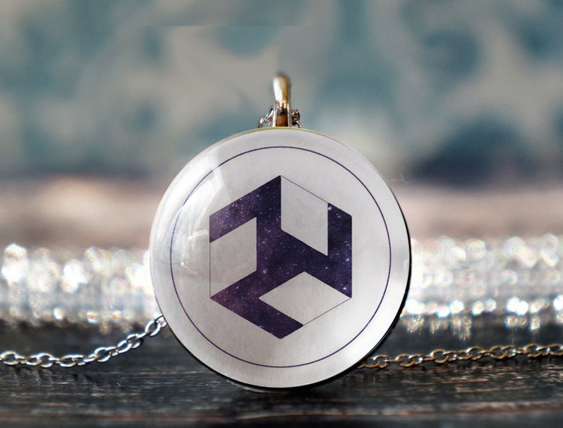 May include: A silver chain necklace with a round pendant featuring a white and purple geometric symbol on a white background.