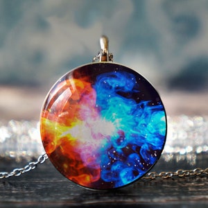 May include: A silver chain necklace with a round pendant featuring a swirling abstract design of blue, red, orange, and yellow colors on a black background.