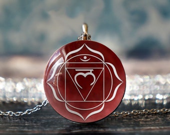 May include: A red and white chakra pendant with a silver chain. The pendant features a stylized symbol of the root chakra, the first chakra in the seven chakra system.