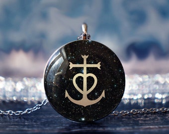 May include: A silver necklace with a round pendant featuring a black background with a gold anchor and cross design. The pendant has a starry sky pattern.