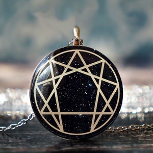 May include: A silver chain necklace with a round pendant featuring a black background with a white five-pointed star and lines forming a pentagon.
