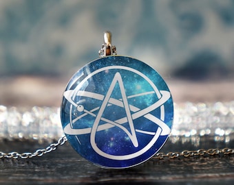 May include: A silver chain necklace with a round pendant featuring a white stylized 'A' inside a circle with a galaxy background.