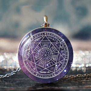 May include: A silver necklace with a round pendant featuring a white circle with a star of David and the names of the archangels in a circle around it. The pendant has a galaxy-like background.