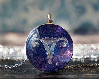 May include: A silver necklace with a round pendant featuring a white outline of a uterus against a galaxy-themed background of purple, blue, and white.