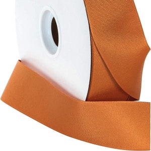 Peut inclure: Une bobine de ruban satiné orange. Le ruban est enroulé autour d'une bobine en carton blanc.