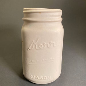 May include: White painted mason jar with the word "Kerr" embossed on the front and "MASON" embossed on the bottom.