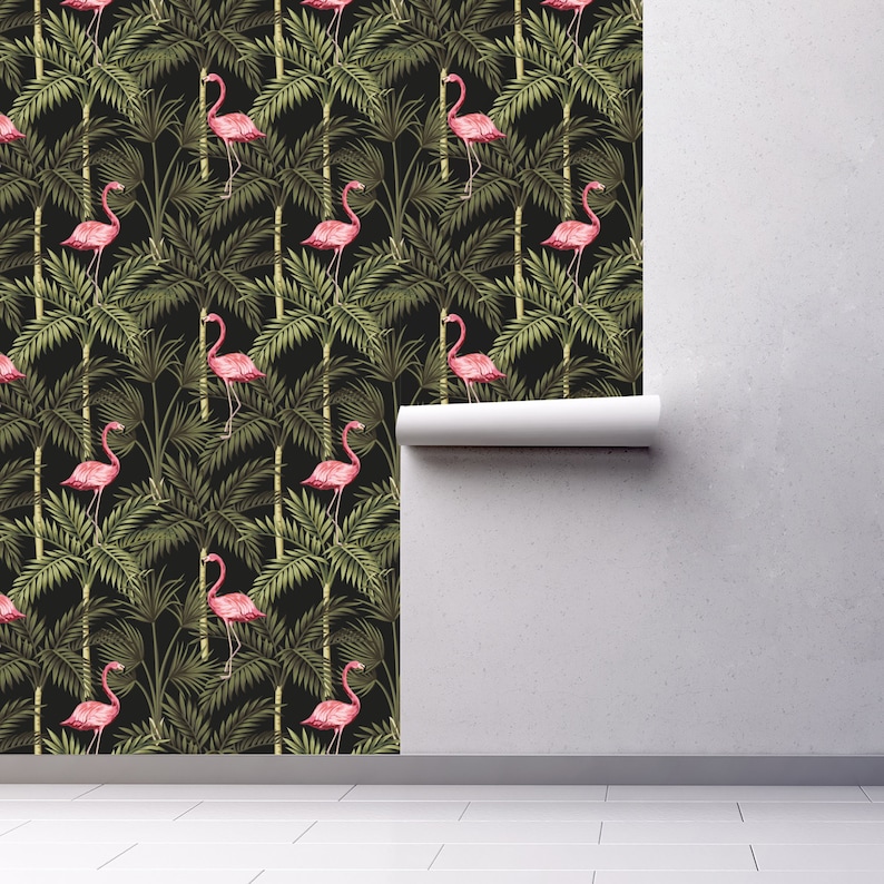 May include: A black and green tropical wallpaper featuring pink flamingos standing in palm trees. The wallpaper is shown partially unrolled on a white wall.