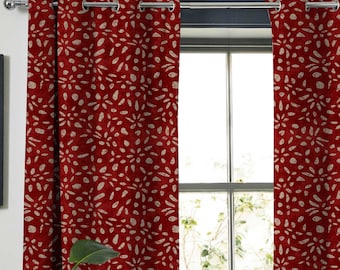 May include: A pair of red curtains with a white floral pattern. The curtains have grommets at the top and are hanging from a silver curtain rod.