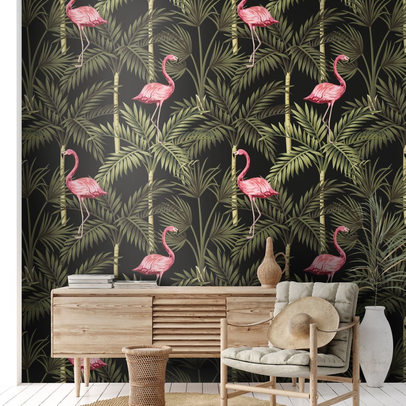 May include: A black and green tropical wallpaper with pink flamingos. The wallpaper is in a living room setting with a wooden table, a wicker basket, and a chair with a straw hat.