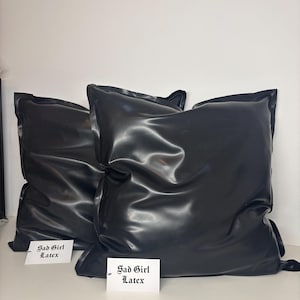 Puede incluir: Dos almohadas de látex negras con el texto "Sad Girl Latex" en etiquetas blancas.