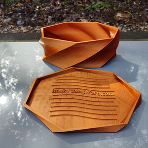 May include: A wooden, octagonal box with a lid. The lid has a wavy, textured surface with the text "makethingsforu.com" engraved on it.