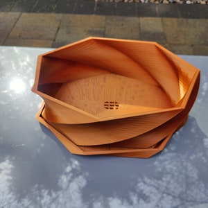 May include: A brown, octagonal, 3D printed planter with a swirling design. The planter has a drainage hole in the bottom.