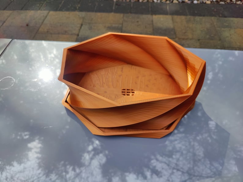 May include: A brown, octagonal, 3D printed planter with a swirling design. The planter has a drainage hole in the bottom.