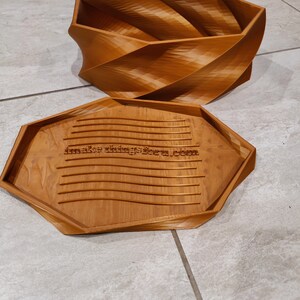 May include: A wooden box with a unique, swirling design. The lid is open and the inside of the box is visible. The box is made of light brown wood and has a natural finish. The box is labeled with the text "make things form.com".