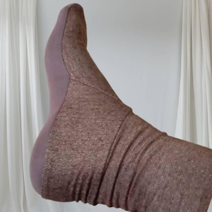 Może przedstawiać: Brązowa skarpeta wykonana z miękkiej, fakturowanej tkaniny. Skarpeta jest podwinięta na górze, odsłaniając wnętrze skarpetki.