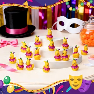 May include: A collection of yellow duck figurines with purple ruffled collars and bunny ears. A black top hat with a pink band, a white mask, and a jar of orange candies are also visible, suggesting a festive theme.