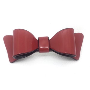 May include: A red bow hair clip with a glossy finish.