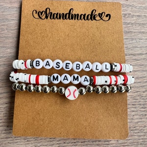 May include: Three handmade bracelets on a brown card. The top bracelet spells "BASEBALL" in white letter beads. The middle bracelet spells "MAMA" in white letter beads. The bottom bracelet has a baseball bead.
