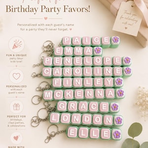 May include: A collection of custom clicker keychains featuring light green bases and pink square tiles with white letters spelling names including Paige, Emma, Penelope, Caroline, Finley, McKenna, Grace, London, and Elle, each with a small purple flower.