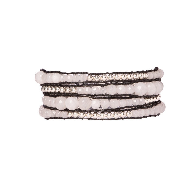 K&ouml;nnte beinhalten: Ein mehrreihiges Armband mit wei&szlig;en Perlen und silbernen Akzenten auf einem schwarzen Band.