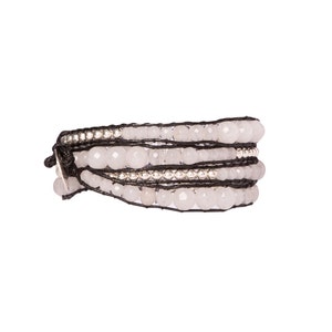 K&ouml;nnte beinhalten: Ein mehrreihiges Armband mit wei&szlig;en Perlen und silbernen Akzenten auf einem schwarzen Band.