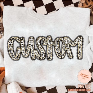 May include: A light gray sweatshirt with the word "CUSTOM" in a leopard print design outlined with black lace. The image also includes a small pink sticker with the text "Vector Creation Studio" and "PNG FILE HANDCRAFTED DESIGN".