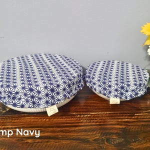 May include: Two round fabric bowl covers with an elasticized edge, featuring a navy blue and white geometric star pattern. Each cover has a small rectangular fabric tag attached to the side. The covers are placed over white ceramic bowls.
