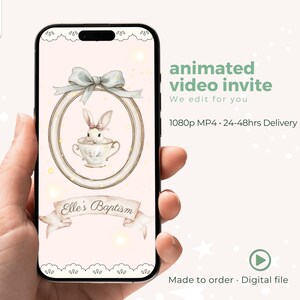 Könnte beinhalten: Ein Smartphone zeigt eine digitale Einladung zur Taufe von Elle. Das Design zeigt eine Aquarellillustration eines Hasen in einer Teetasse, umrahmt von einer Schleife. Der Text lautet "animated video invite" und "Made to order. Digital file."