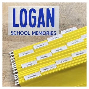 May include: A yellow file organiser with tabs labelled with school grades, from Preschool to 12th Grade. A white rectangle with the name "LOGAN" in blue and "SCHOOL MEMORIES" is in the background.