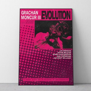May include: A framed poster with a vibrant pink and black design. The poster features the text "GRACHAN MONCUR III EVOLUTION" and a photograph of a musician playing a trombone. The poster also lists the names of other musicians.