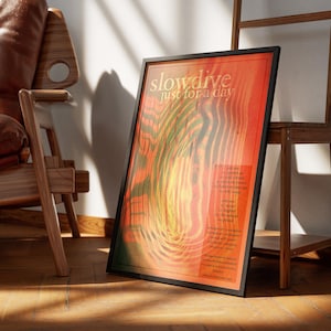 Może przedstawiać: Oprawiony plakat z napisem "slowdive just for a day" w czarnej ramie. Plakat ma czerwono-pomarańczowe tło z zielonymi i ż&oacute;łtymi falistymi liniami. Drewniane krzesło i drewniana p&oacute;łka znajdują się w tle.