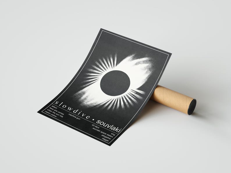 May include: A monochrome poster with the band name "slowdive" and album title "souvlaki". The design features a central dark circle with radiating white lines. It is propped against a brown cardboard tube.