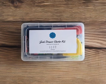 May include: A clear plastic container filled with various tools and supplies. The container has a yellow label that reads "Junk Drawer Starter Kit. Handy Items for Everyday Life." The label also includes a list of contents.
