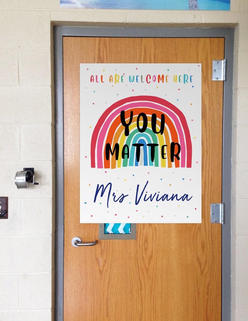 May include: A colorful rainbow with the words "You Matter" in black text and the words "All are welcome here" and "Mrs. Viviana" in blue text. The background is white with small colorful dots.