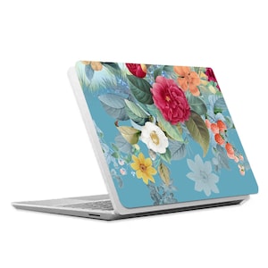 May include: A laptop with a floral design on the back. The design features a variety of flowers in shades of pink, red, white, and yellow on a light blue background.