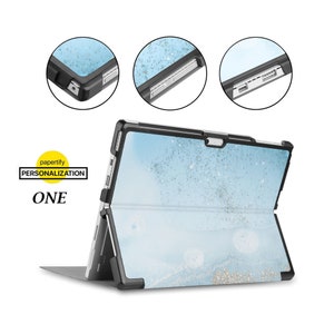 May include: A blue and gold patterned case for a Microsoft Surface tablet. The case features a built-in kickstand and a clear back panel. The case is shown in a folded position, with the tablet screen facing the viewer. The case is made from durable plastic and has a soft, textured finish. The case is designed to protect the tablet from scratches, bumps, and drops. The case is also compatible with the Surface Pen.
