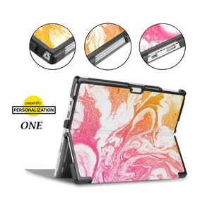 Könnte beinhalten: Eine schwarze Hülle mit einem pinkfarbenen, orangen und weißen Marmormuster für ein Microsoft Surface Tablet. Die Hülle hat einen Ständer und eine integrierte Tastatur. Der Text "papertify PERSONALIZATION ONE" ist auf der Hülle sichtbar.