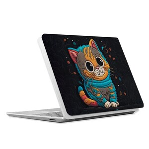 May include: A white laptop with a black and colorful cat design on the lid. The cat is wearing a blue and orange space suit and has a friendly expression.