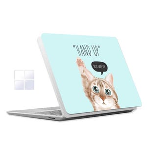 May include: A white laptop with a light blue design featuring a cartoon cat with the text "HAND UP" and "NOT GIVE UP".