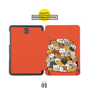 May include: A red and black tablet case featuring a cartoon illustration of a group of cats in a cup. The case is designed for a tablet with a camera on the back.