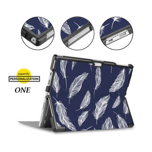 May include: A black case with a white feather pattern for a Microsoft Surface Pro tablet. The case has a kickstand and a built-in keyboard.